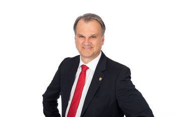 Stadtamtsdirektor Uwe Deutschbauer mit dunkelm Sakko, weißem Hemd und roter Krawatte