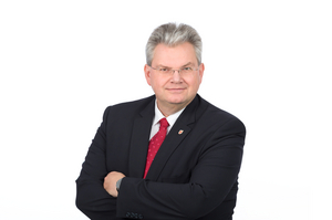 Stadtrat Mag. Harald Kronsteiner mit schwarzen Sakko, weißem Hemd und roter Krawatte